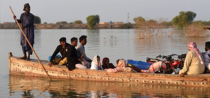 Internally displaced people use a boat to cross a flooded area at Dadu in Sindh province, Pakistan. October 27, 2022. Asif Hassan/AFP via Getty Images