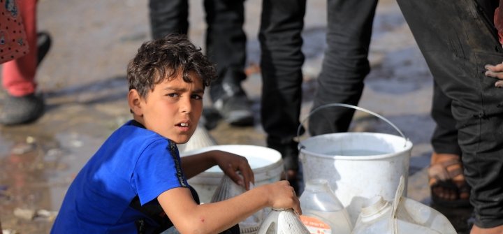 A Palestinian child wearing a blue shirt waits in line for clean water in Rafah, Gaza, on March 16. 