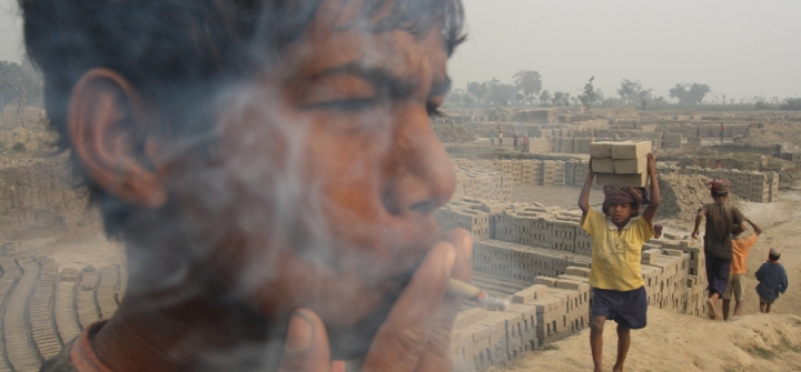 A 15-year-old child laborer, smokes a bidi (leaf-rolled tobacco cigar) while working in a brick factory at Ghanashyampur village in Murshidabad, 350 km north of Kolkata, India. 