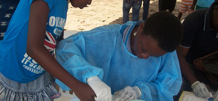 Céline Mabot Yobo collects a drop of blood from a young girl for immunological analysis.