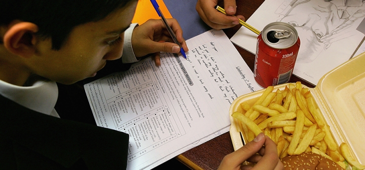 A London school student eats a hamburger and chips as part of his lunch which was brought from a fast food shop near his school, on October 5, 2005 in London, England.