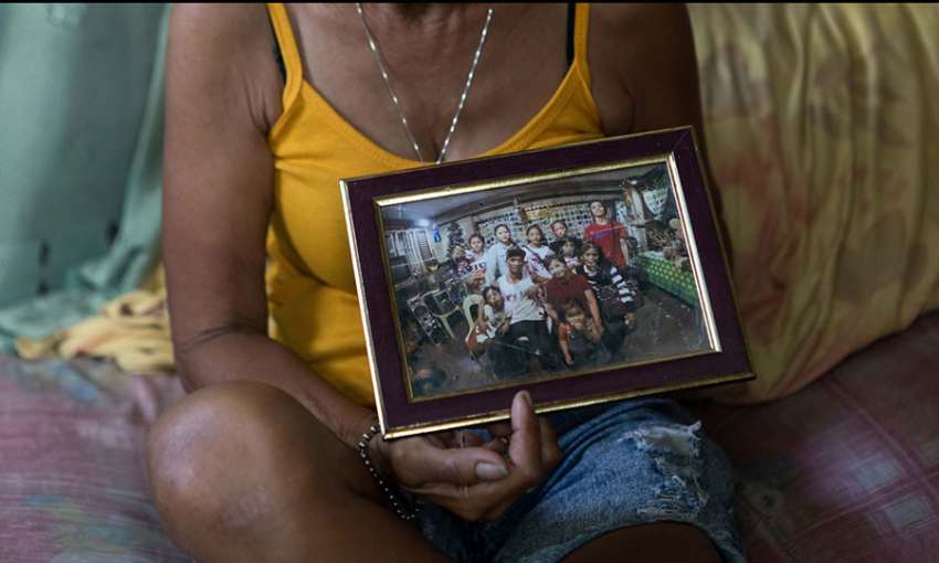 Carmelita, who lost her son in the Philippines anti-drug wars, holds a family photo