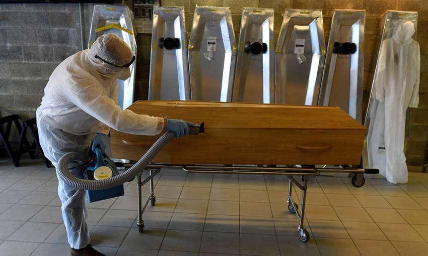 A Chaudoir funeral home employee disinfects the coffin of a COVID-19 victim in Namur, Belgium on April 20, 2020. Image: John Thys/AFP via Getty Images