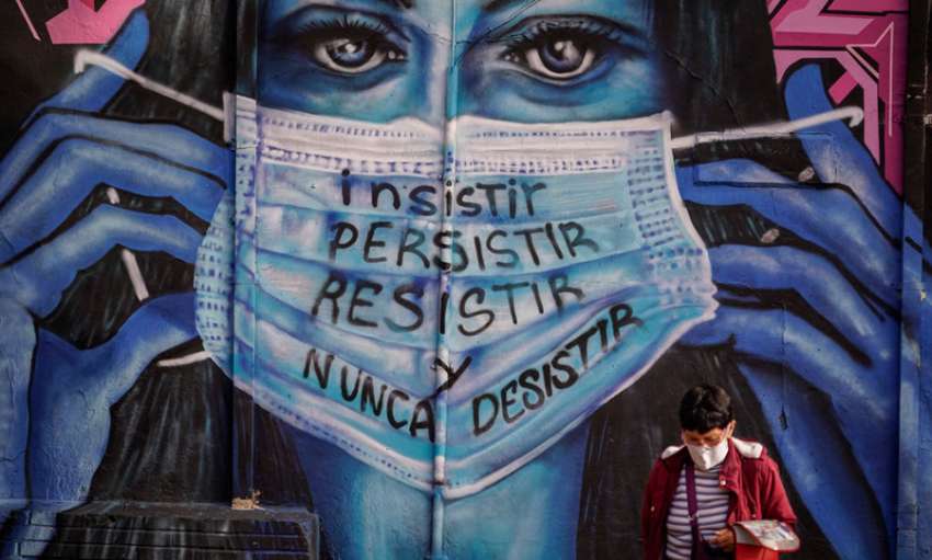 A woman walks in front of a mural that reads “insist, persist, resist and never give up.” Bogota, Colombia, June 21, 2021. Image: Diego Cuevas/Getty