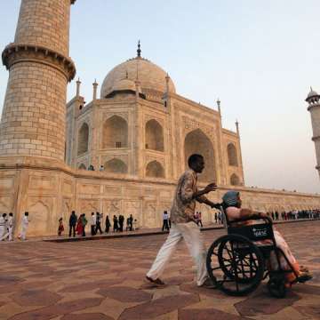 A man pushes a woman in a wheelchair at the Taj Mahal in Agra, India.