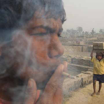 A 15-year-old child laborer, smokes a bidi (leaf-rolled tobacco cigar) while working in a brick factory at Ghanashyampur village in Murshidabad, 350 km north of Kolkata, India. 