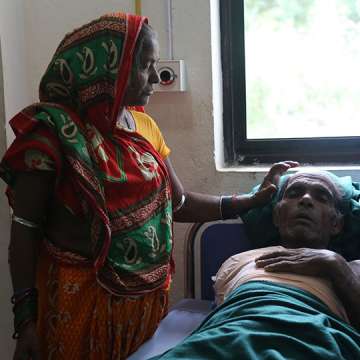Urmila Devi Poddar stands beside her husband Ladayan Poddar, who accidentally touched a live wire and suffered burns so severe that his right arm had to be amputated. 