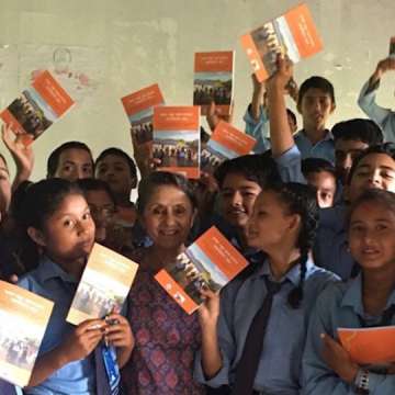Physician-advocate Rita Thapa shares a booklet on cardiovascular disease risk factors with friends at a secondary school in Dang, Nepal on August 24, 2018. (Image courtesy)