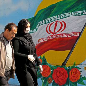 Iranians walk past a mural displaying their national flag in Tehran on March 4, 2020. Image: Atta Kenare/AFP/Getty
