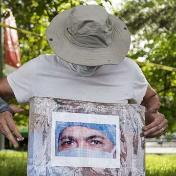 Artist Jorge Rodríguez holds a photo of Ydelfonso Decoo, an immigrant doctor who died of coronavirus complications. Queens, May 27, 2020. Image: Pablo Monsalve/VIEWpress via Getty