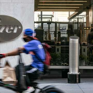 A cyclist wearing a mask spins past Pfizer Inc. headquarters in New York City. July 22, 2020. Image: Jeenah Moon/Getty