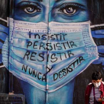 A woman walks in front of a mural that reads “insist, persist, resist and never give up.” Bogota, Colombia, June 21, 2021. Image: Diego Cuevas/Getty
