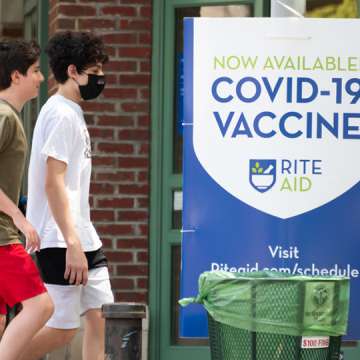 Young people walk by a sign that reads, "Now available! COVID-19 vaccine" in TriBeCa, New York City. May 27, 2021. Image: Noam Galai/Getty