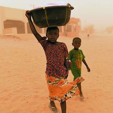A sandstorm blasts a girl carrying linen followed by her brother in Goundam, Mali, June 3, 2015. Image: Philippe Desmazes/AFP/Getty