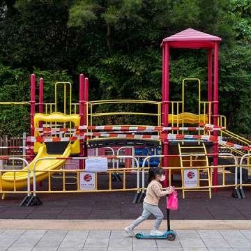 A kid rides on an electric scooter past a closed playground in Hong Kong. which reintroduced strict Covid social restrictions to control the spread of the Omicron variant. Jan. 15, 2022 Image: Miguel Candela/SOPA Images/LightRocket via Getty