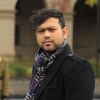 Pranab Chatterjee wearing a black coat and plaid scarf (head shot)