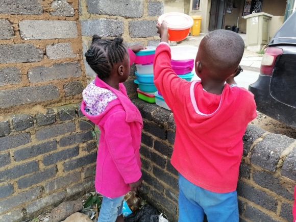 Children picking up food containers at a community kitchen. 