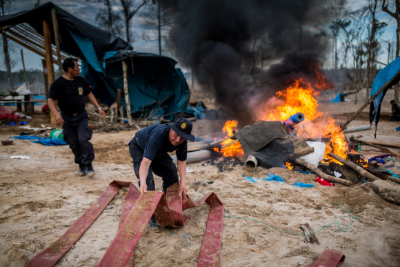 Flames and plumes of black smoke rise over an illegal gold mining camp after authorities set fire to machinery and gasoline used by the miners, during an operation in illegal gold mining area of La Pampa, in Madre de Dios, southern Peruvian jungle on July 13, 2015.