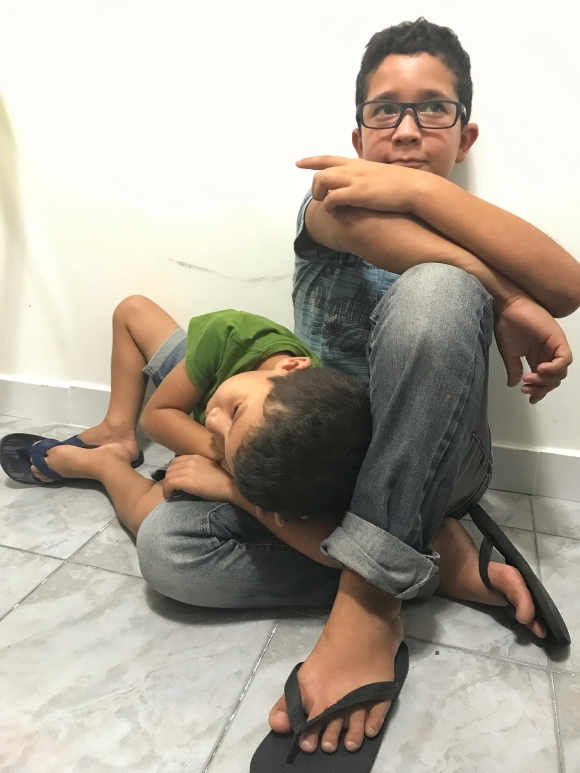 Jorge, 6, lies on his older brother’s lap while they wait for Gilberto to finish his physical therapy appointment at the IPESQ clinic.
