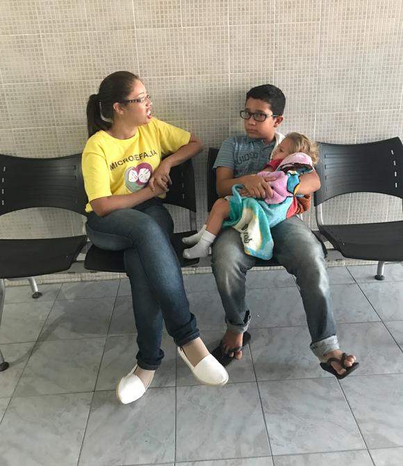 Marcos, 10, holds Gilberto and chats with others at the IPESQ clinic while waiting for his mother.