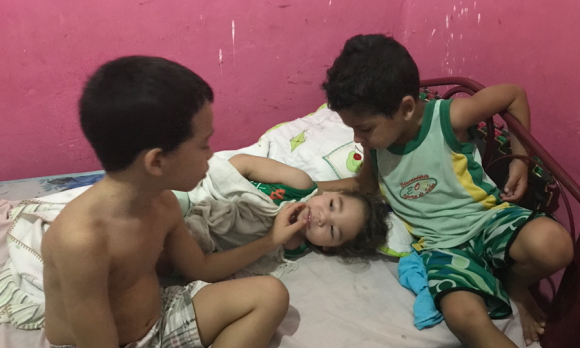 Rafael peers curiously at Davi, while Miguel gently touches his face.