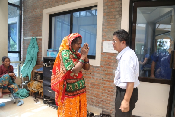 Outside the Nepal Cleft and Burn Center in Kirtipur, Shankar Rai is stopped by Urmila Devi Poddar, whose husband (hospitalized inside) has had his arm amputated after a bad electrical burn.