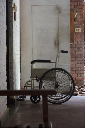 A wheelchair sits empty in the corner of a clinic. 